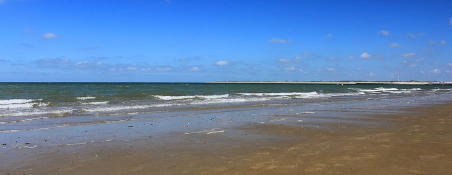 Waves with whitecaps flood the sandy beach.Wellen mit weißen Schaumkronen überfluten den Sandstrand .