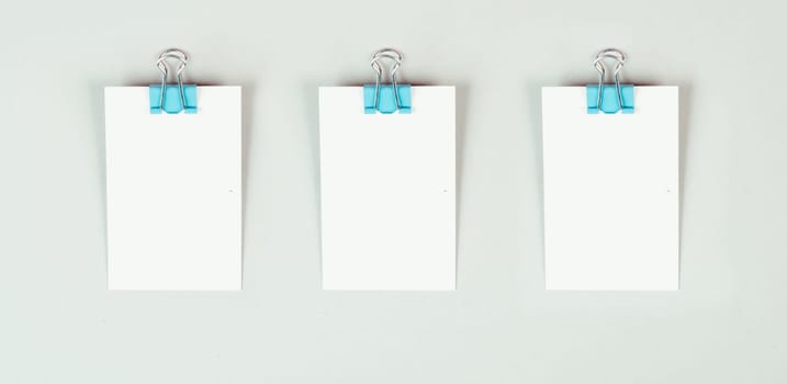 Blank white papers with a paperclip on a gray colored background, copy space for text, reminder or message in the office, communication concept