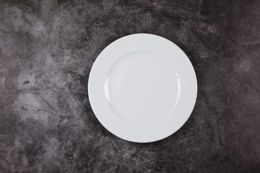 A white dinner plate on a grey and white marble surface