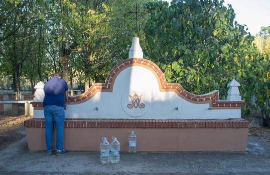 La Codosera, Spain - August 21th, 2021: Sanctuary of Our Lady of Chandavila. Local man filling bottles at holy fountain