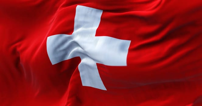 Close-up view of the swiss national flag waving in the wind. Switzerland is a landlocked country located in Europe. Fabric textured background. Selective focus