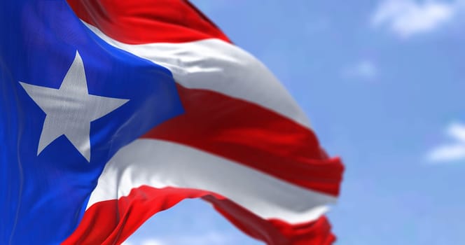 Flag of Puerto Rico waving in the wind on a clear day. Puerto Rico is a Caribbean island and unincorporated territory of the United States