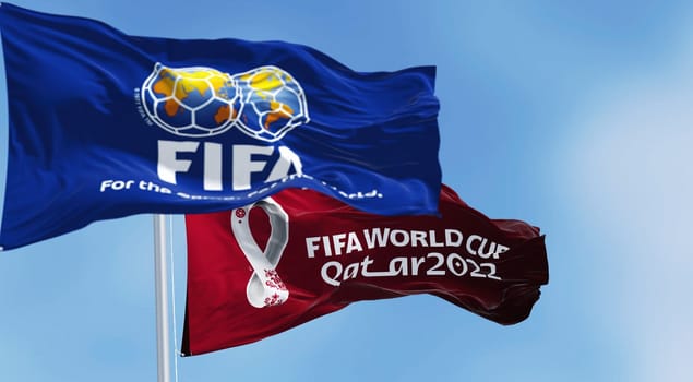 Doha, Qatar, January 2022: Flags with FIFA and Qatar 2022 World Cup logo waving in the wind. The event is scheduled in Qatar from 21 November to 18 December 2022