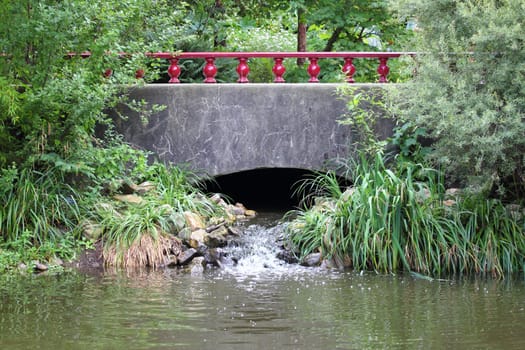 Bridge with red handrails, forest in the background.Brücke mit rotem Geländer, Wald im Hintergrund.
