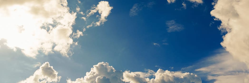 Blue sky with clouds and sun shines bright in the daytime in summer