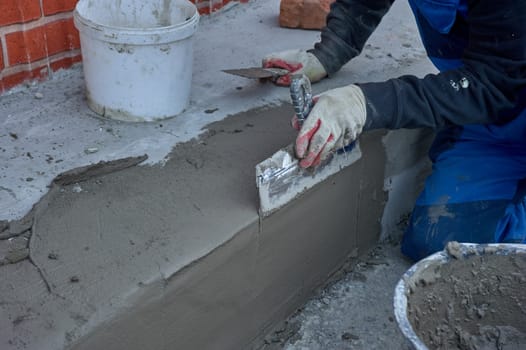 a worker uses a spatula to distribute the cement mixture along the ramp. High quality photo