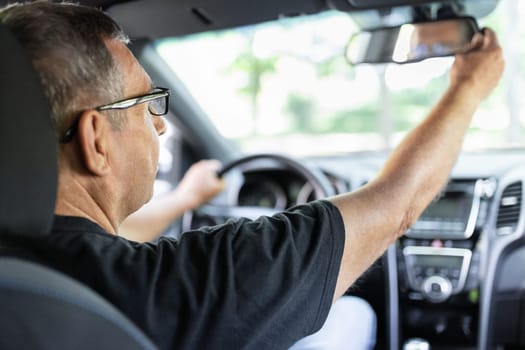 Happy senior in his 70s driving a car