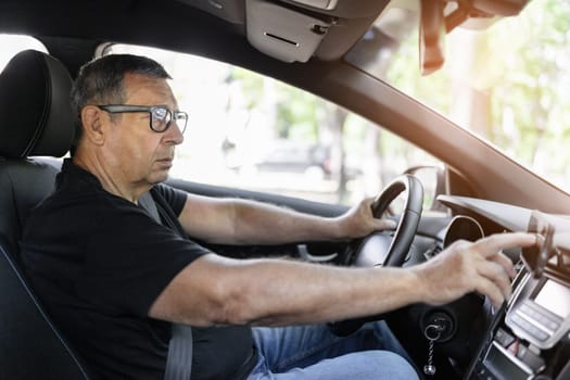 Senior behind the steering wheel using navigation and looking for directions