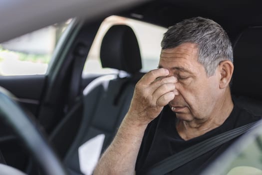 Tired pensioner in his 70s, dring in a car