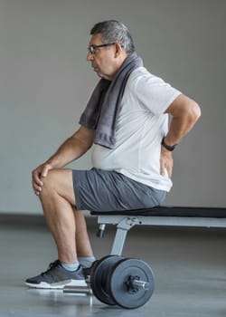 Active senior man in gym with back pain