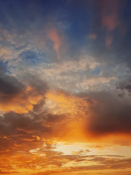Beautiful sunset sky with colorful orange clouds over the horizon, vertical celestial background