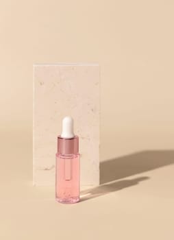 Glass cosmetic Dropper Bottle near travertine stone on light yellow, close up, mockup. Exotic skincare beauty product, essential oil or serum. Pastel minimal composition..