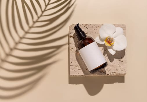 Glass One pump bottle on stone near white orchid flowers on light yellow close up, label mockup, Palm leaf hard shadows. Skincare handmade beauty product, serum or lotion. Exotic natural cosmetics..