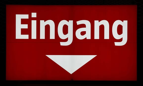 illuminated red sign at the entrance to a store in Germany. Translation: entrance