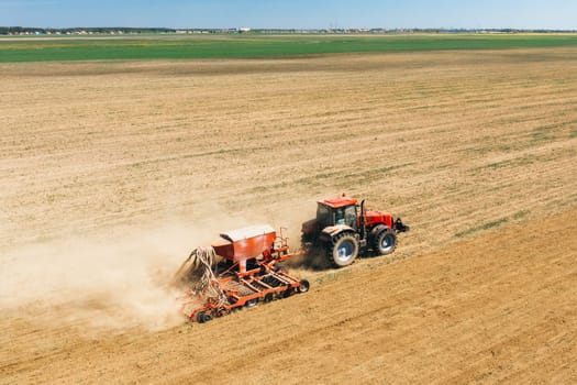 Aerial View. Tractor With Seed Drill Machine Sowing The Seeds For Crops In Spring Season. Beginning Of Agricultural Spring Season. Countryside Rural Field Landscape.