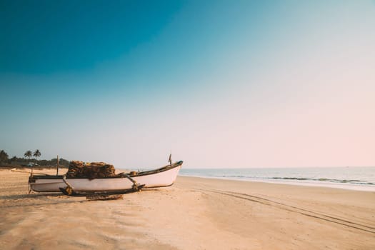 Goa, India. Old Wooden Fishing Boat Standing On Sea Ocean Beach. Tropical Palms On Background.