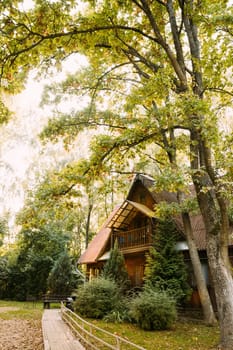 Tourist Guest House For Rest. Wooden House In Forest In Autumn Sunny Day. Wooden Boarding Path Way Pathway Leading To Tourist House. Resort In Wooden Guest House.