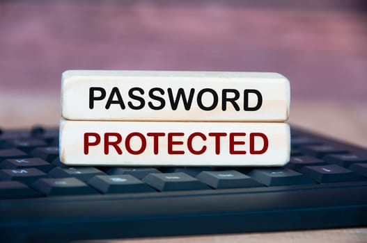 Password protected text on wooden block on top of keyboard. Password security concept