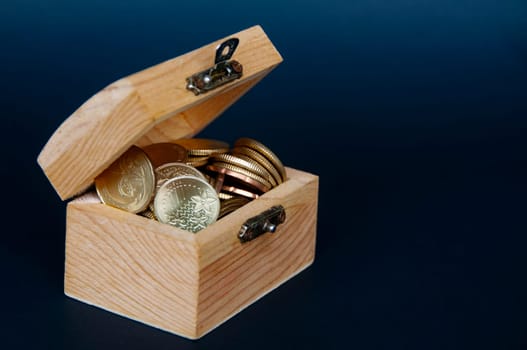 Gold coins inside treasure chest on dark background cover. Copy space and wealth concept