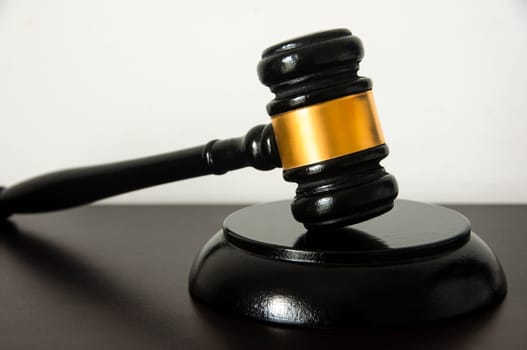 Straight view of lawyer gavel on wooden table with white background. Law concept
