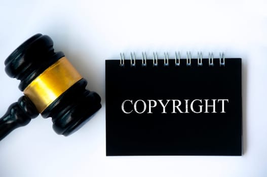 Copyright law text on black notepad and gavel on white background cover. Copyright law concept