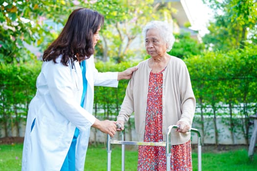 Doctor help Asian elderly woman disability patient walk with walker in nursing hospital, medical concept.