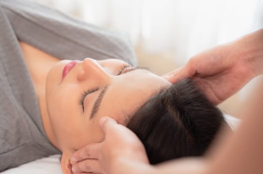 Relaxed and calm girl having spa facial massage in beauty salon. Traditional oriental massage therapy and beauty treatment. Spa skin and body care concept