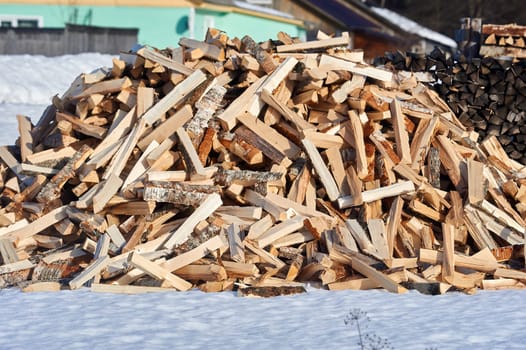 A pile of split firewood lies on the snow in winter. High quality photo
