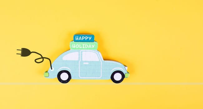 Small blue electric car with a cable for recharging, vacation trip with eco power