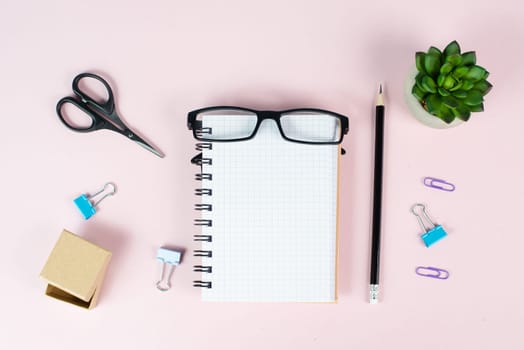 Empty notebook with a pen, eyeglasses and a cactus on a pastel colored desk, brainstorming for new ideas, writing a message, home office workplace