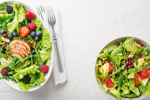 Fresh salads with lettuce and fruit on white background top view with space for text. Healthy food.