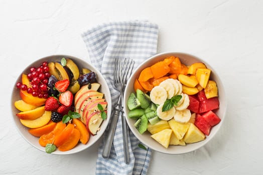 Bowls of healthy fresh fruit salads on white background, top view