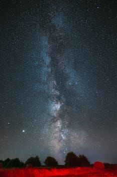 Milky Way Galaxy In Night Starry Sky Above Haystack In Summer Agricultural Field. Night Stars Above Rural Landscape With Hay Bale After Harvest. Agricultural Concept.