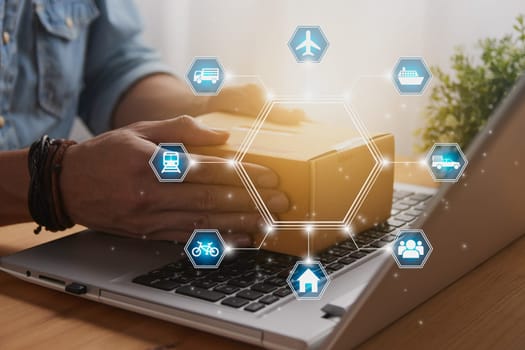 Hand of Casual Businessman or Entrepreneur Catch Parcel or Box on Laptop and Blue Hexagon Logistic or Transportation Icon. SME Online Business and E-commerce Concept for Work at Home
