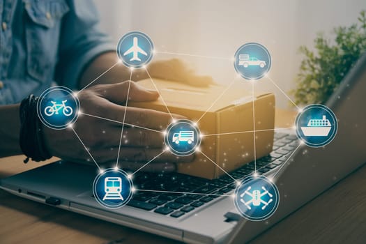 Hand of Casual Businessman or Entrepreneur Catch Parcel or Box on Laptop and Blue Logistic or Transportation Icon. SME Online Business and E-commerce Concept for Work at Home in Vintage Tone