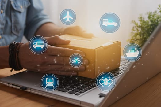Hand of Casual Businessman or Entrepreneur Catch Parcel or Box on Laptop and Blue Logistic or Transportation Sign. SME Online Business and E-commerce Concept for Work at Home