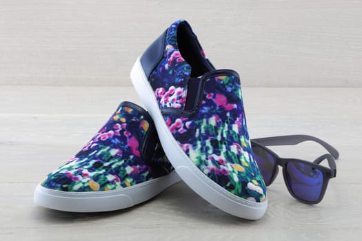 A pair of colourful pumps on wood background with sunglasses