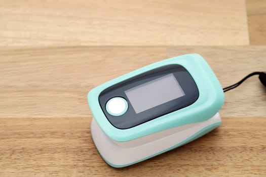 Pulse oximeter device on wooden table, healthcare monitoring concept
