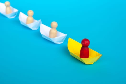 Leadership Concept - Red people figure on yellow paper ship origami leading the rest of the people figure on white paper ship. Copy space.