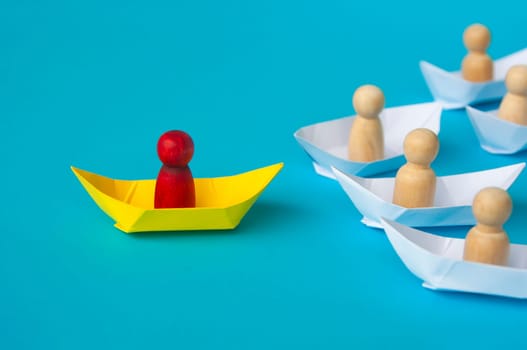 Leadership Concept - Red people figure on yellow paper ship origami leading the rest of the people figure on white paper ship. Copy space.