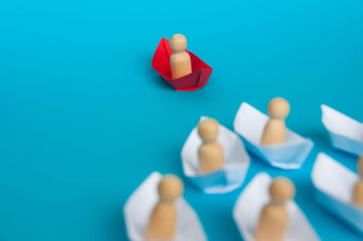 Leadership concept - People figure on red paper ship origami leading the rest of the people figure on white paper ship. Copy space.
