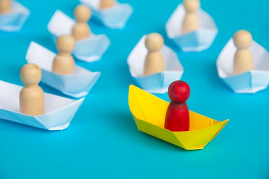 Leadership Concept - Red people figure on yellow paper ship origami leading the rest of the people figure on white paper ship. Copy space.