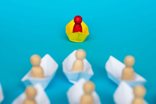 Leadership Concept - Red people figure on yellow paper ship origami leading the rest of the people figure on white paper ship. Copy space.