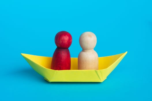 Couples on yellow paper ship with blue background. Relationship concept.