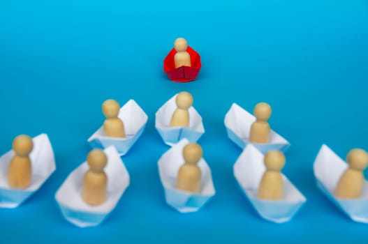 Leadership Concept - Wooden figure on red paper ship origami leading the rest of the figure on white paper ship. Copy space.