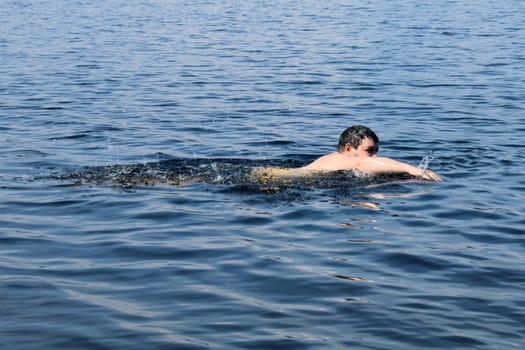 A bearded man swims in the sea. Concept of summer vacation, healthy lifestyle.