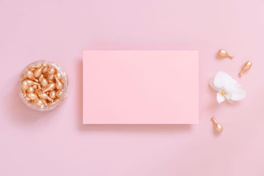 Blank card near Face serum capsules and white orchid flower on pink top view. Mockup. Facial treatment. Exotic minimal flat lay with copy space..