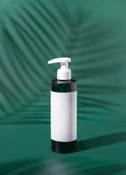 One pump Plastic bottle with blank label on green, palm leaf hard shadows, close up, mockup. Skincare beauty product, facial cleaner or lotion. Natural cosmetics..