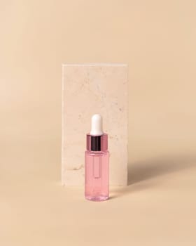 Glass cosmetic Dropper Bottle near travertine stone on light yellow, close up, mockup. Exotic skincare beauty product, essential oil or serum. Pastel minimal composition..