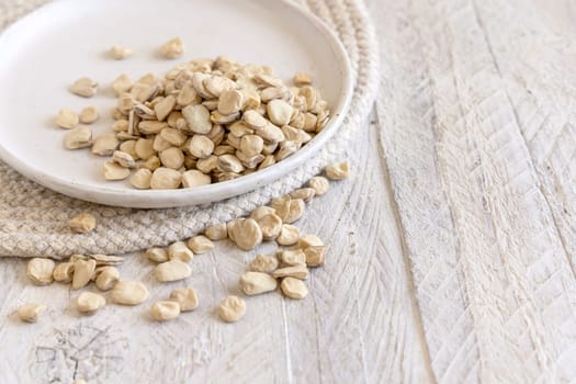 Plate of raw dry Grass pea close up on wood. Healthy, protein source for vegan and vegetarian diet. Traditional Italian apulian cuisine ingredient. Legumes known as Cicerchia, Vetch, Blue Sweet Pea
